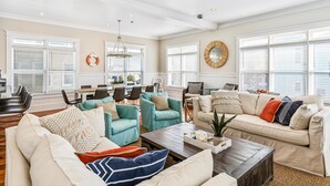 A spacious living room with a high ceiling, large windows with blinds, a dining area with a table and chairs, and a cozy seating area with a sofa and armchairs. - 2 Rooftop decks, pool/elevator. Downtown IOP, 1 blk from beach. Pet friendly! (Isle of Palms)