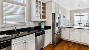 A modern kitchen with white cabinetry, stainless steel appliances, and a black countertop. - 2 Rooftop decks, pool/elevator. Downtown IOP, 1 blk from beach. Pet friendly! (Isle of Palms)