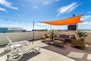 A rooftop terrace with outdoor furniture, a large orange shade, and string lights. - 2 Rooftop Decks | Downtown IOP | Pool | Elevator | 1 Blk From Beach | Pets (Isle of Palms)