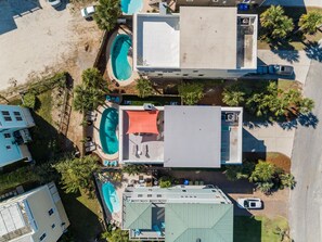 Vista aérea de un resort con varias piscinas, un patio cubierto y un edificio grande con techo plano.