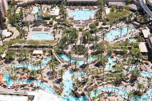 A resort with multiple swimming pools, palm trees, and sun loungers.