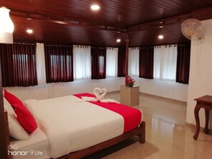 Relax in this inviting room with a large bed, wooden paneling, and a charming table with a vase of flowers.