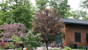 Ein Gebäude mit Ziegelaußenwand und Gründach, umgeben von einem Garten mit verschiedenen Pflanzen und einem Baum mit rosafarbenen Blüten.