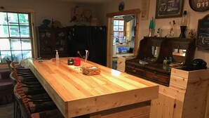 Eine Küche mit einer Holztresen, Barhocker, einem Kühlschrank und einer Mikrowelle.