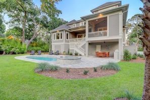 A two-story house with a pool, outdoor seating, and a covered patio area.