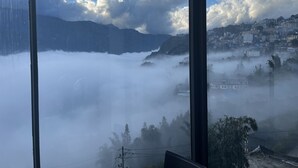 A view through a window of a mountainous landscape with a city in the background. - Sapa Valley View Hotel (Sa Pa)