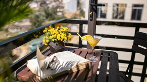 A table with a book, glasses, a drink, and a bouquet of yellow flowers on a balcony. - Sapa Valley View Hotel (Sa Pa)