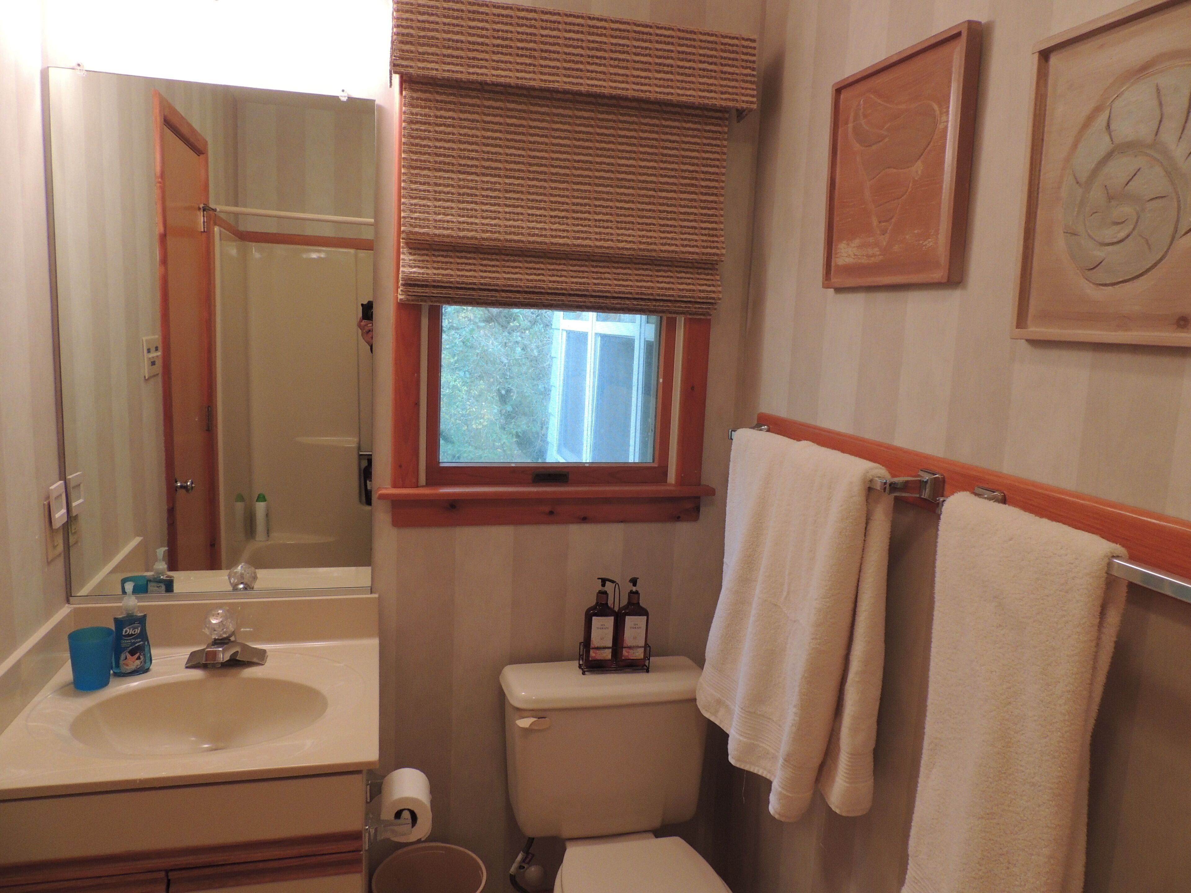 A bathroom with a sink, toilet, and window.
