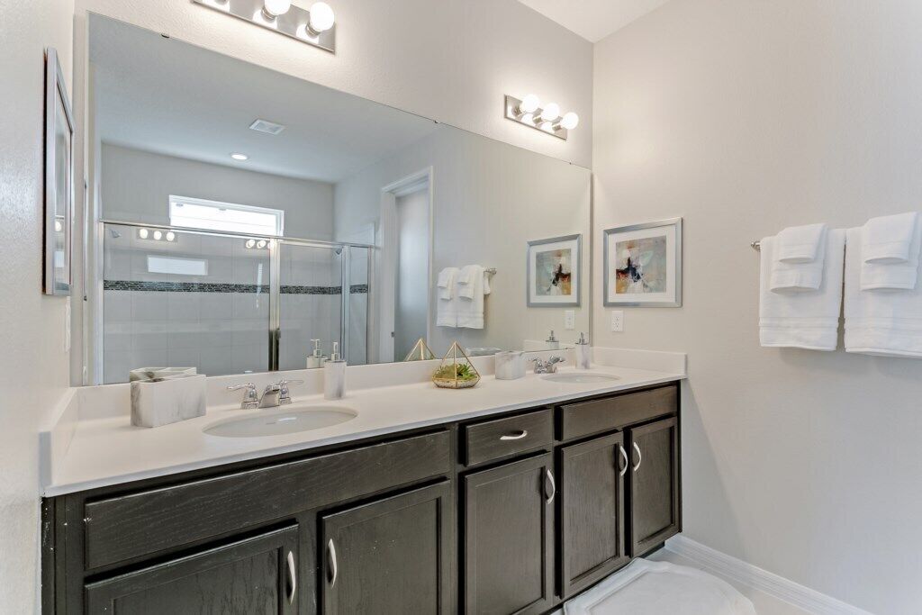 Une salle de bain moderne avec un meuble-lavabo à deux vasques, un grand miroir et un espace douche.