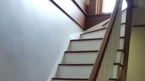 Una escalera de madera con barandilla que sube a un piso superior.