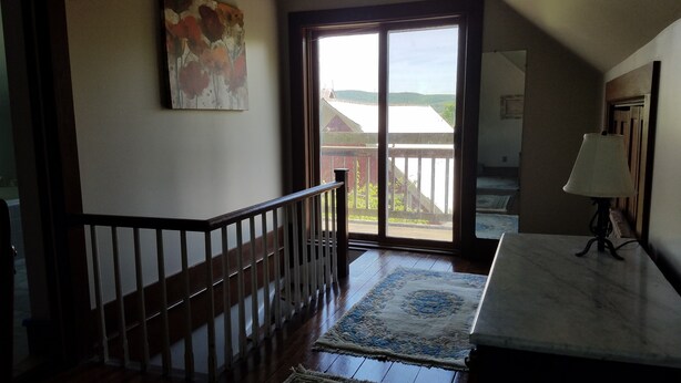 Una escalera con barandillas de madera que conduce a un gran ventanal corredizo.