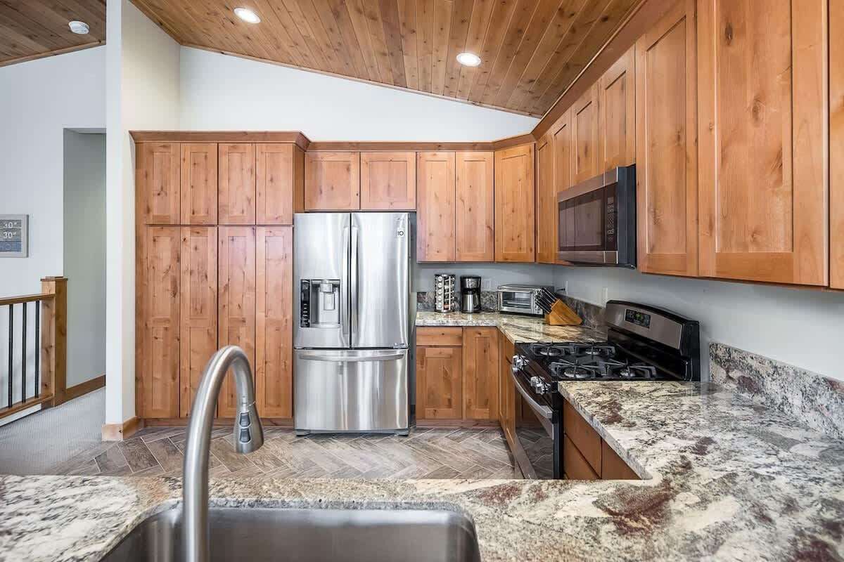 Una cocina con armarios de madera, electrodomésticos de acero inoxidable y encimera de granito.