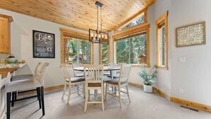 A dining area with a wooden ceiling, a chandelier, and a view of the outdoors through large windows. - Deck, Bikes, Newer Build in Upper Kings Beach (Kings Beach)
