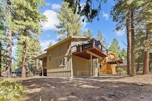 Une cabane dotée d’un porche abrité, entourée de grands arbres.