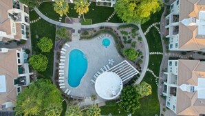 Vista aérea de uma área residencial com piscina, alpendre coberto e vegetação ao redor.