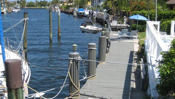 A waterfront dock with boats, a wooden walkway, and a row of beach chairs. - Bright Spacious 3bed/2bath Intracoastal Home (Deerfield Beach)