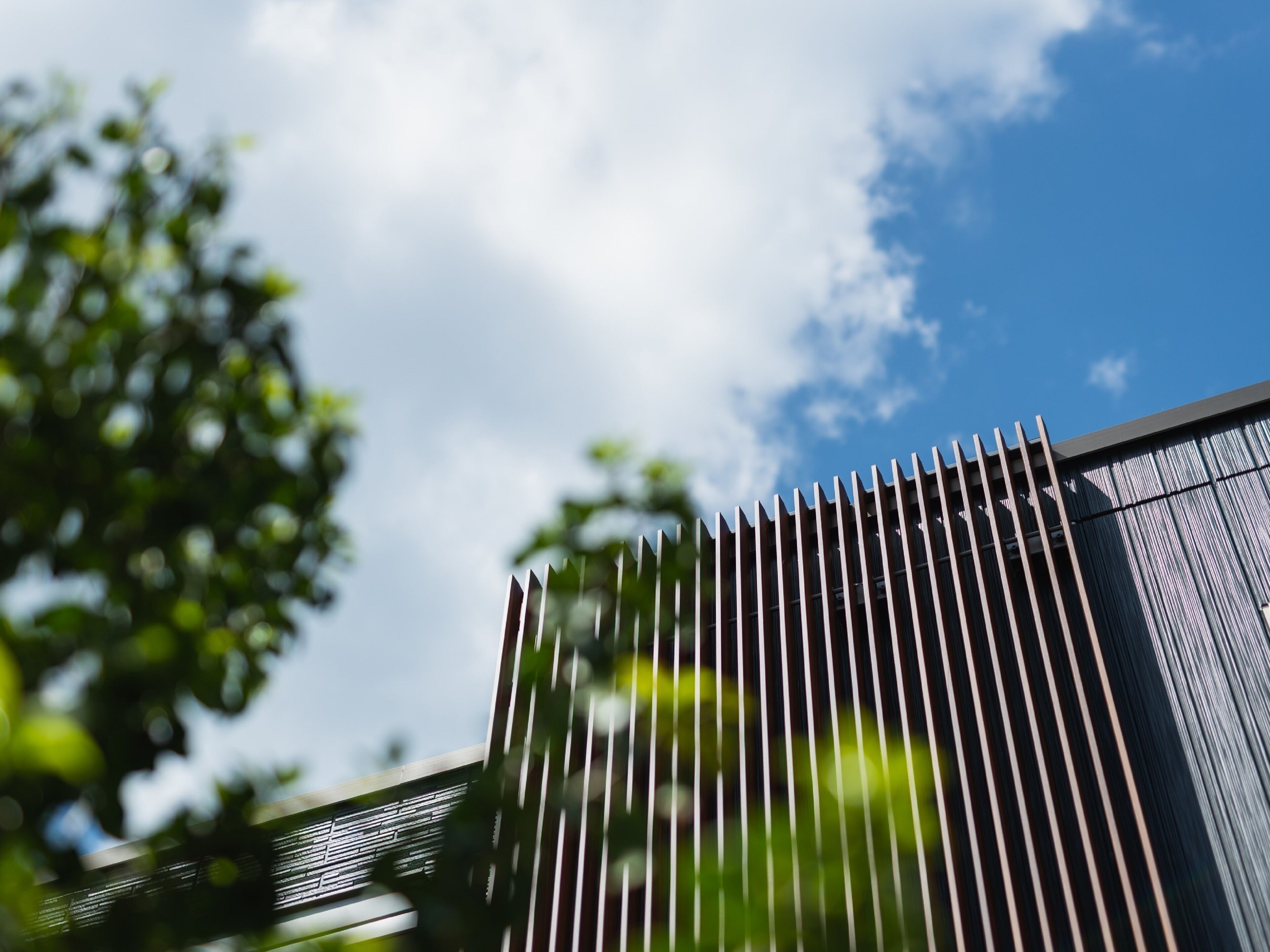 A modern building with a vertical metal facade and a clear blue sky in the background.