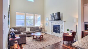 A spacious living room with a fireplace, a large TV, and a cozy seating area. - Windswept Cottage - Oyhut Bay Seaside Village (Ocean Shores)