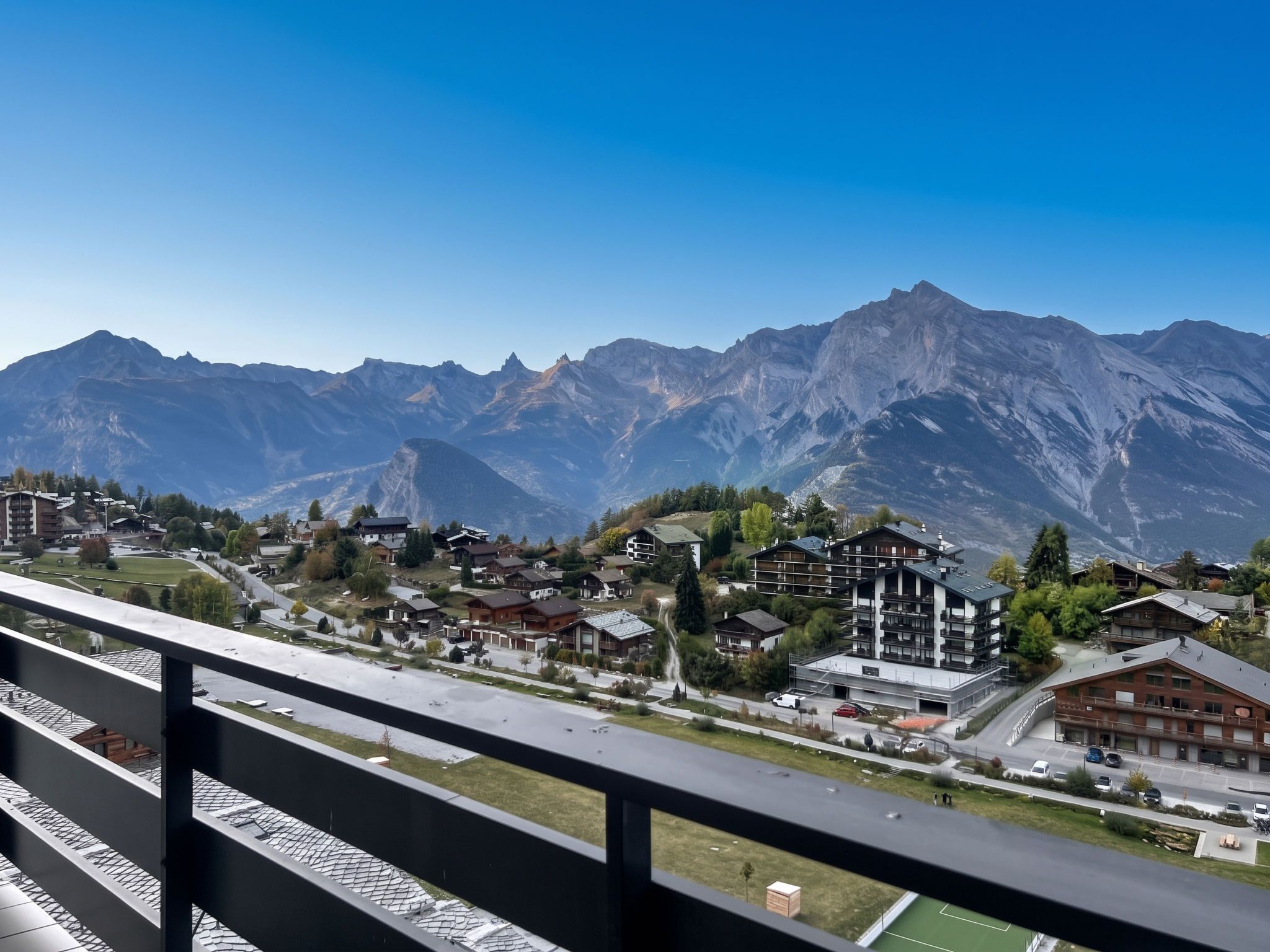 A mountain town with modern buildings, a clear sky, and a view of the mountains.