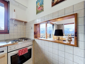 Eine Küche mit Herd, Backofen und einem Fenster mit Blick auf Berge.