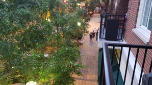 Un paseo peatonal con árboles y farolas, bordeado por edificios de fachadas de ladrillo y balcones.