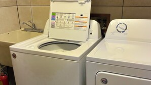 A front-loading washer and dryer in a kitchen with a tiled backsplash and wooden cabinets above. - Country home just minutes from town (Port Angeles)