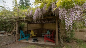 A wooden pergola with purple wisteria hanging over a patio area with colorful Adirondack chairs. - Country home just minutes from town (Port Angeles)