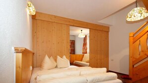 A bedroom with a wooden headboard, a bed with white bedding, and a wooden staircase. - Falkner by Interhome (Längenfeld)