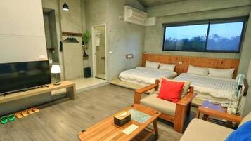 A modern hotel room with a large bed, a TV, a wooden coffee table, and a view of the outdoors.