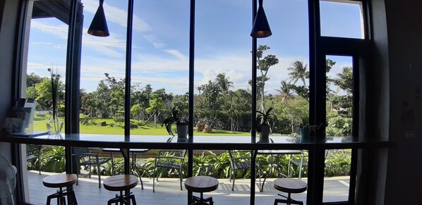 A room with large windows, a view of a green landscape, and several tables and chairs. - Lin's Forest (Hengchun)
