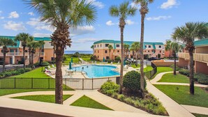 Ein Resort mit Swimmingpool, umgeben von Palmen und Blick auf den Ozean.