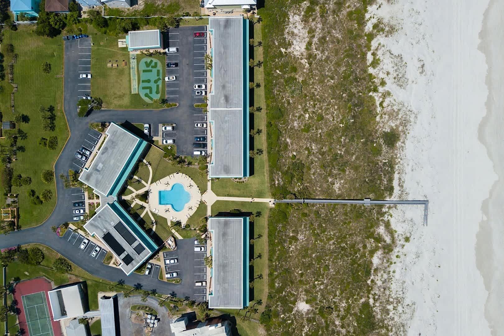 An aerial view of a coastal hotel with multiple buildings, a swimming pool, and a beach.
