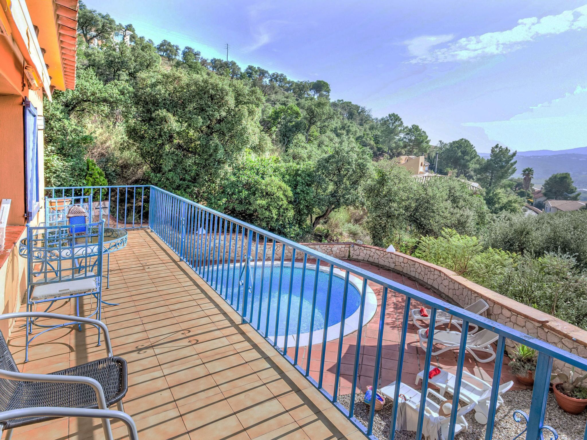 Ein Pool mit blauer Absicherung, umgeben von einer Holzterrasse und Gartenmöbeln.