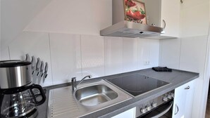 Una cuina moderna amb un rentaplat de superfície inoxidable, una cafetera i una placa de cocció.