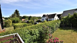 Zona residencial amb una casa blanca, un cotxe i un jardí ben cuidat.