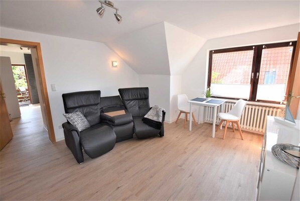 A modern living room with a black leather sofa, a small white table, and a white radiator.