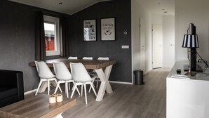 Een moderne eetruimte met een houten tafel en witte stoelen, een raam met gordijnen, en twee posters met inspirerende teksten aan de muur.