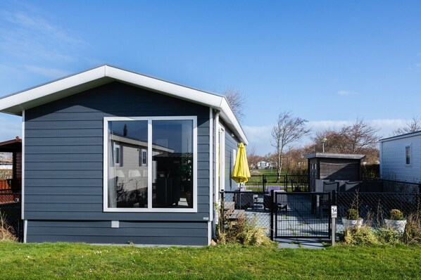 A modern single-story house with a large window and a covered porch area. - CS 34 - Vakantiepark Callassande (Callantsoog)