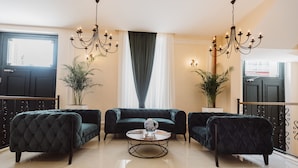 Una habitación con un sofá verde oscuro, una mesa de centro redonda y dos candelabros.
