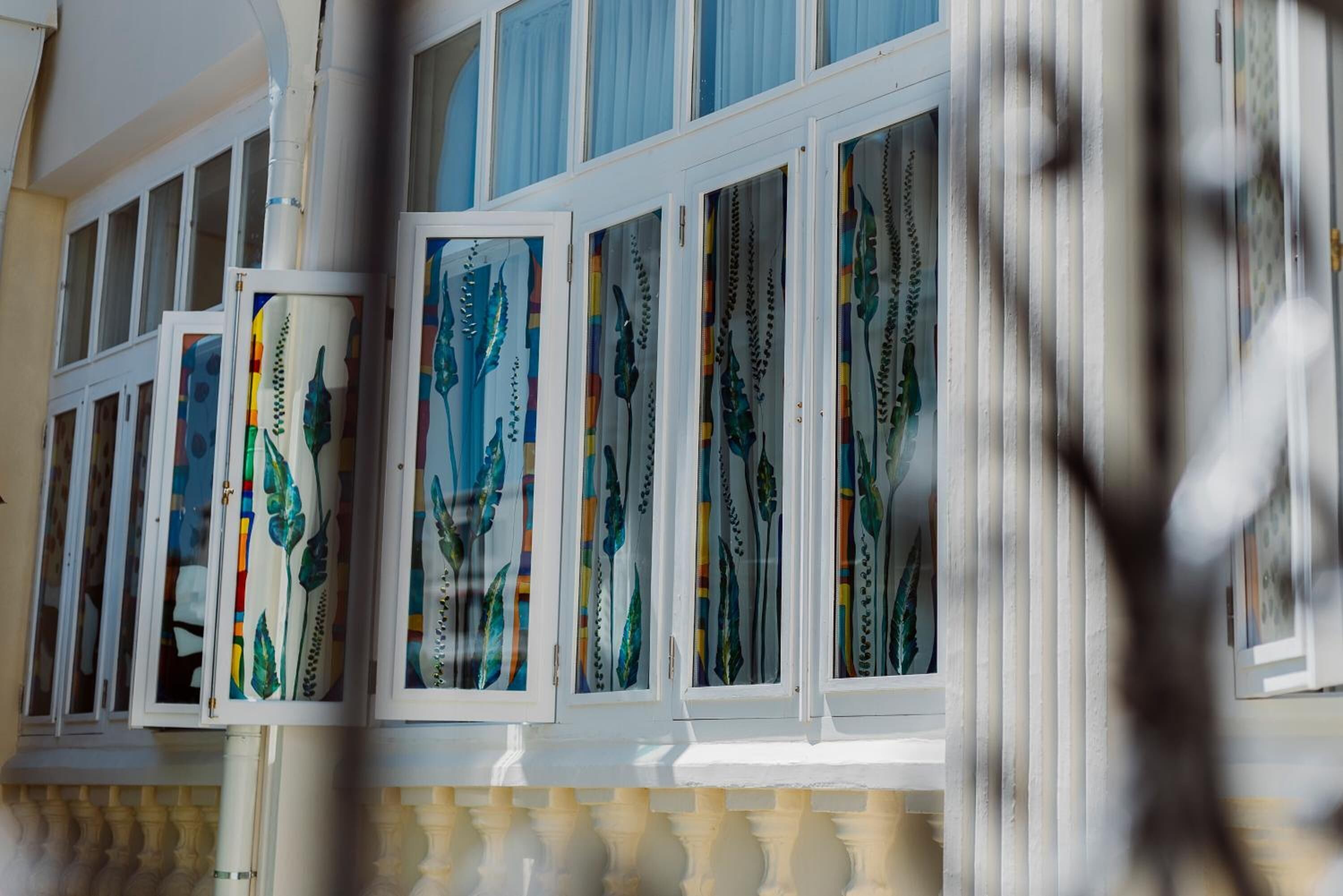 Fachada de edificio con múltiples ventanas adornadas con cortinas de colores y diseños.