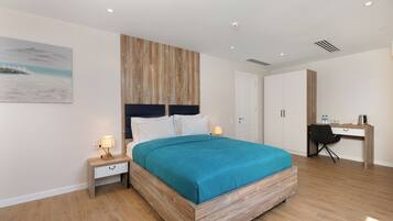 A modern bedroom with a wooden headboard, a teal bedspread, a desk, and a chair.