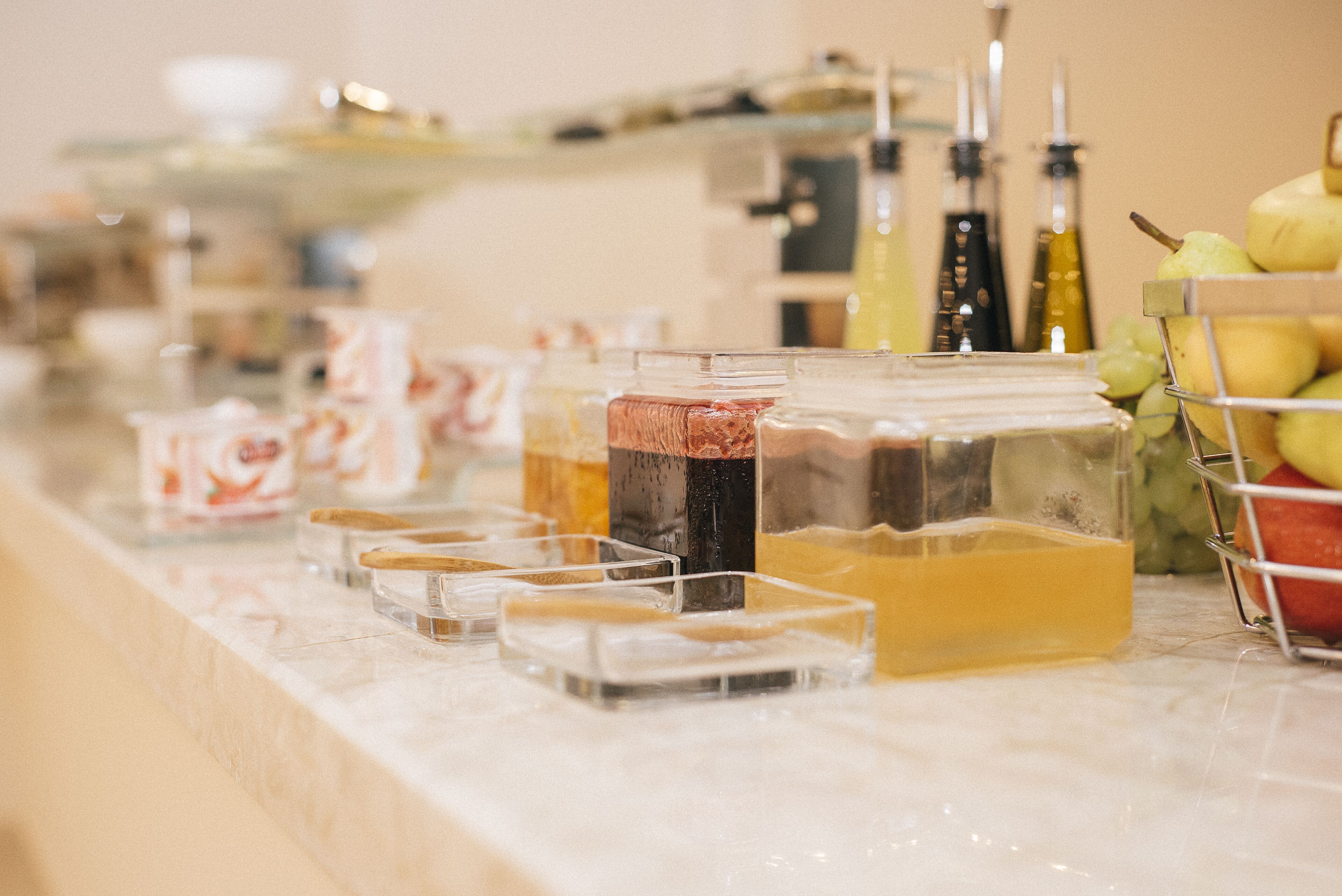 Un buffet proposant une variété de plats et de boissons, notamment des pots de sauces et un panier de fruits.