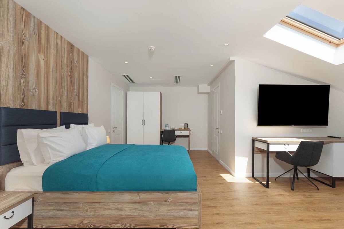 Une chambre à coucher moderne avec un lit, un bureau et un téléviseur.