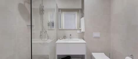 A modern bathroom with a glass-enclosed shower, a white sink, and a toilet.