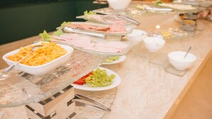 Un bufé con diversas opciones de comida, incluyendo fiambres, queso y verduras.