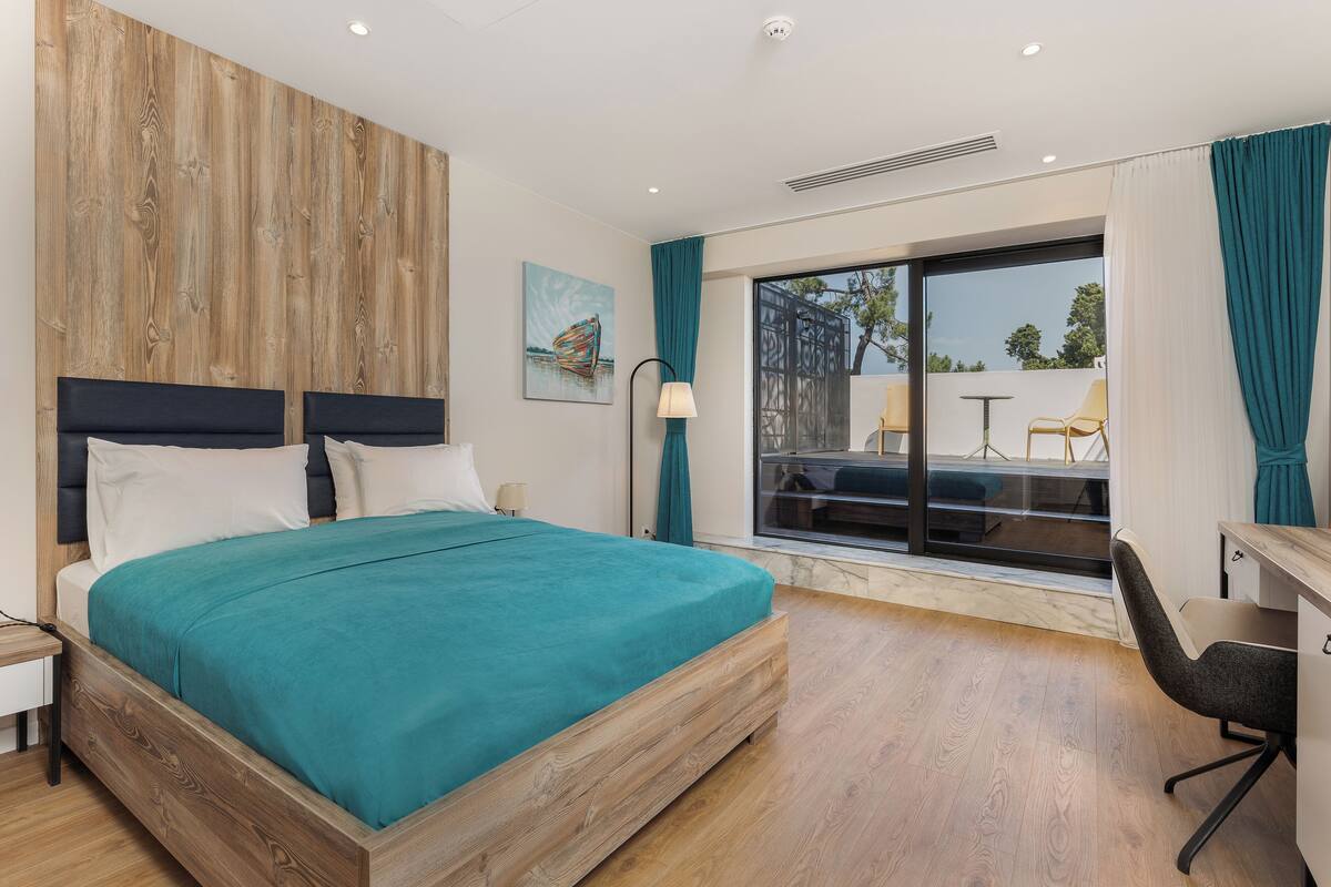 Une chambre moderne avec un grand lit, un bureau et une vue sur l’extérieur.