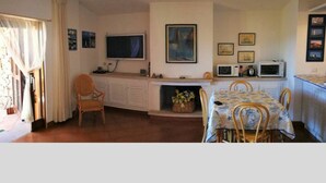 Een knus woongedeelte met een eethoek, kitchenette en een open haard.