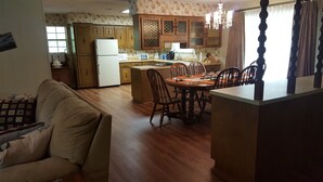 A kitchen with wooden cabinets, a refrigerator, a microwave, and a dining area with a table and chairs. - Backyard splendor!!! (Story)