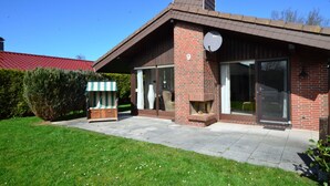 A brick house with a sloped roof, a satellite dish, and a large window. - Holiday home Kenter Tossens (Butjadingen)