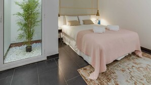 Un dormitorio moderno con una cama grande, una mesita de noche, una lámpara y una planta en maceta.